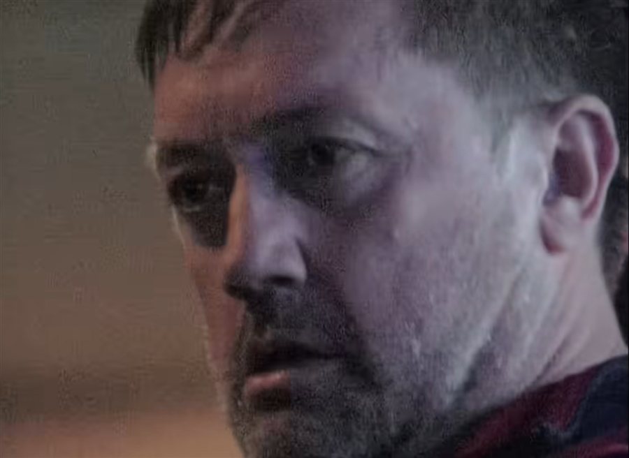 film still: a man looking down, lit by a screen