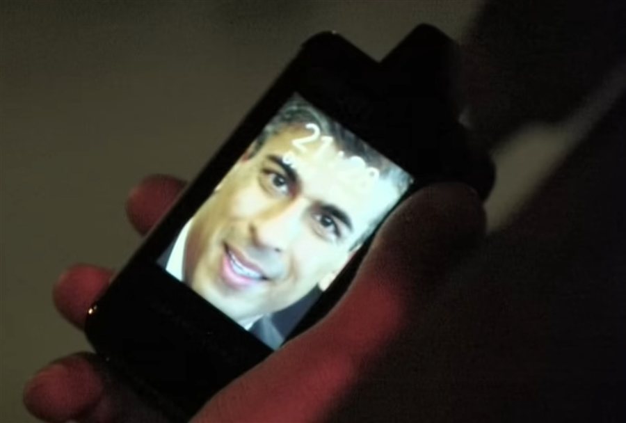 film still: a hand holding a phone showing a smiling face