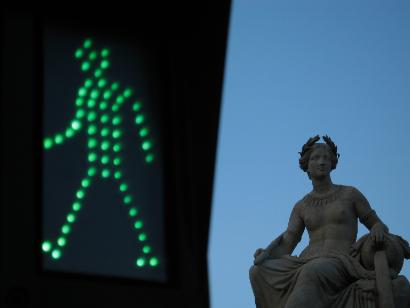 green pedestrian crossing light beside a classical statue